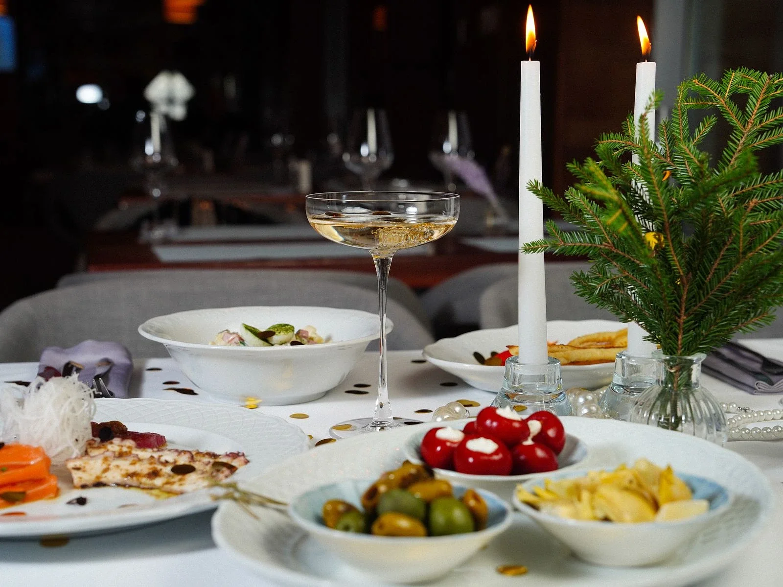Varmt inrett matbord med levande ljus, vin och vackert upplagda rätter i en exklusiv restaurangmiljö